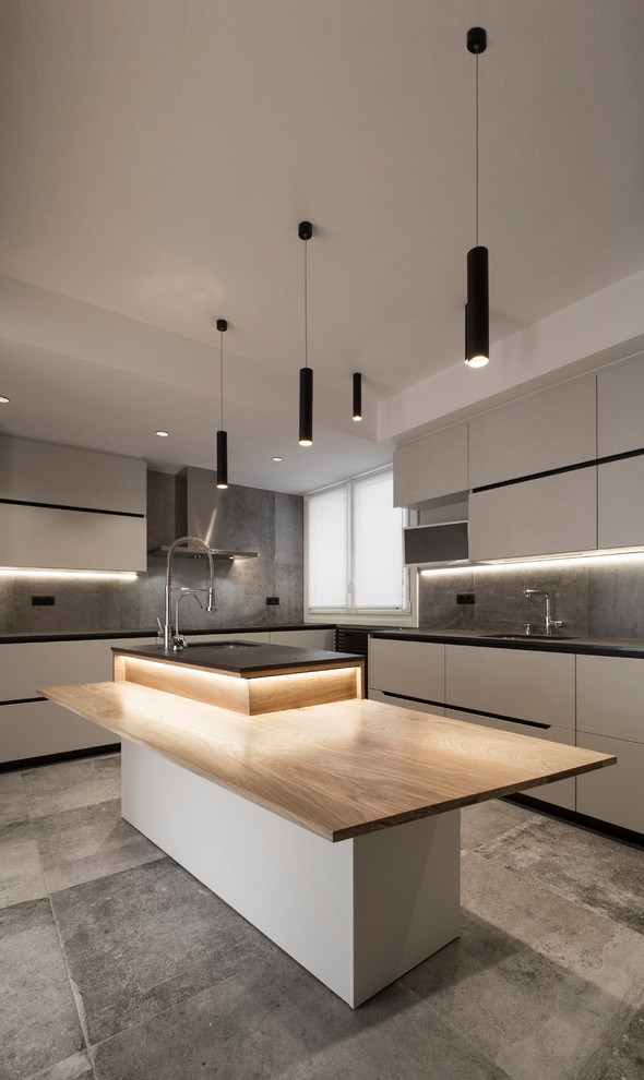 Geschlossene Moderne Küche in L-Form mit flächenbündigen Schrankfronten, Küchenrückwand in Grau, Keramikboden, Kücheninsel, grauem Boden, schwarzer Arbeitsplatte, Unterbauwaschbecken und grauen Schränken in Bilbao