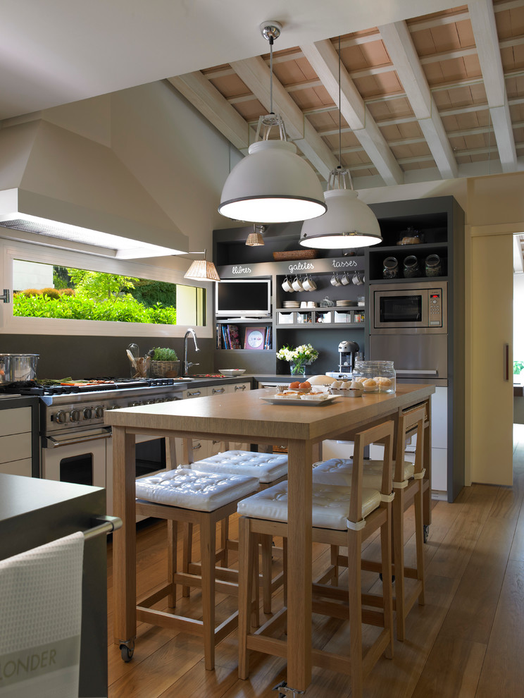 Mittelgroße Moderne Wohnküche in U-Form mit offenen Schränken, grauen Schränken, Küchenrückwand in Grau, Küchengeräten aus Edelstahl und braunem Holzboden in Barcelona