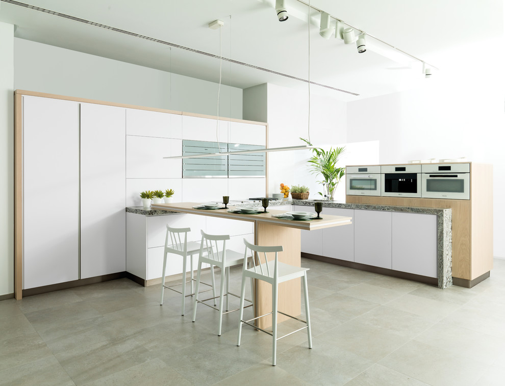 This is an example of a large contemporary u-shaped enclosed kitchen in Other with flat-panel cabinets, white cabinets, wood worktops, white appliances, ceramic flooring and a breakfast bar.