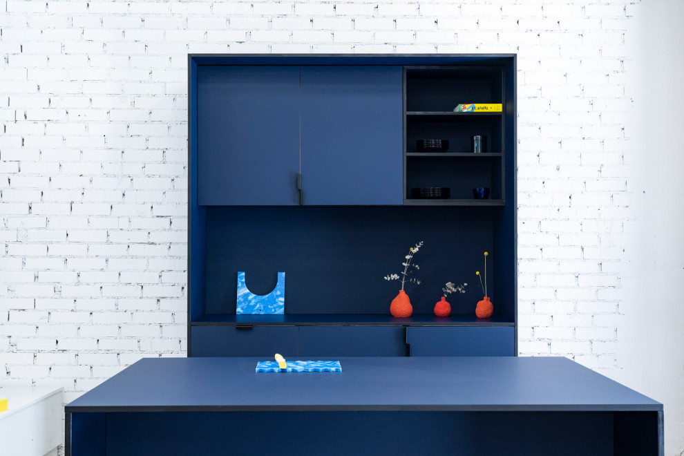 Idéer för att renovera ett mellanstort industriellt blå linjärt blått kök med öppen planlösning, med en nedsänkt diskho, luckor med profilerade fronter, blå skåp, laminatbänkskiva, blått stänkskydd, stänkskydd i metallkakel, integrerade vitvaror, betonggolv, en köksö och grått golv