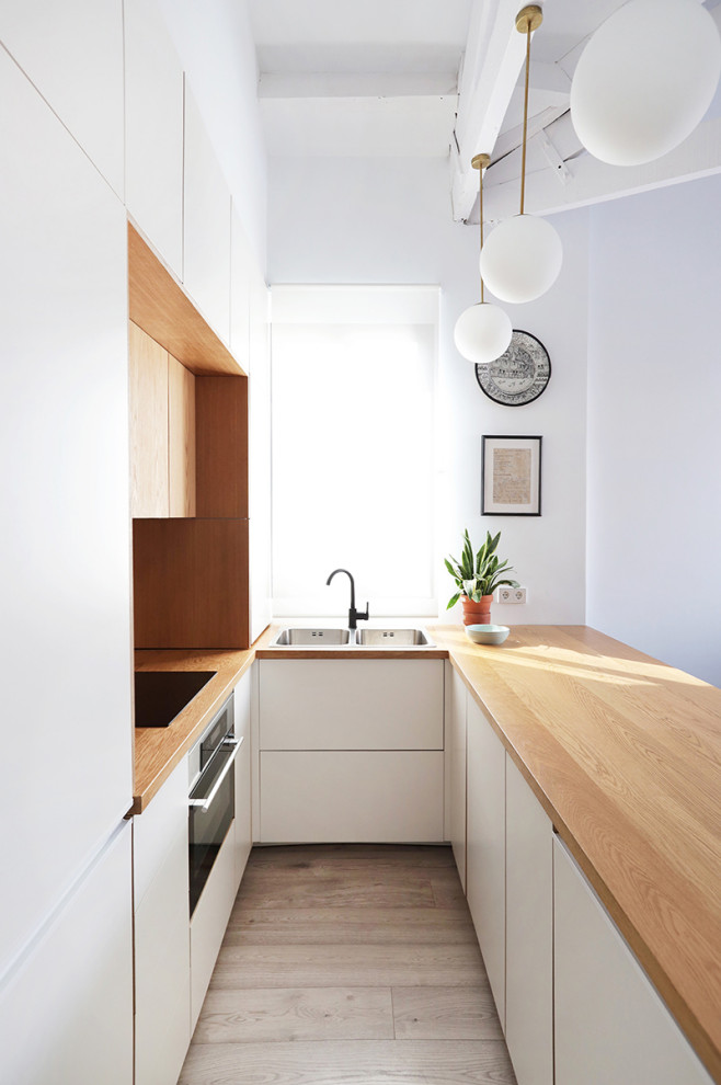 Medium sized scandi u-shaped kitchen/diner in Madrid with a built-in sink, shaker cabinets, white cabinets, wood worktops, stainless steel appliances, light hardwood flooring, a breakfast bar, brown floors, brown worktops and a drop ceiling.