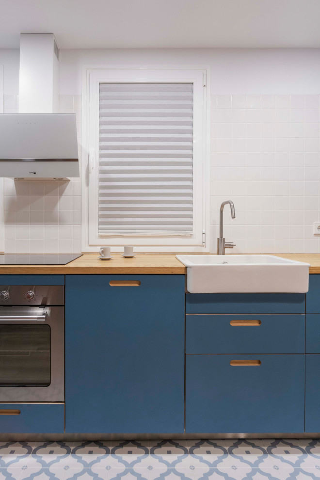 Foto på ett litet minimalistiskt brun linjärt kök med öppen planlösning, med en nedsänkt diskho, skåp i shakerstil, blå skåp, träbänkskiva, stänkskydd i keramik, rostfria vitvaror, klinkergolv i keramik och blått golv