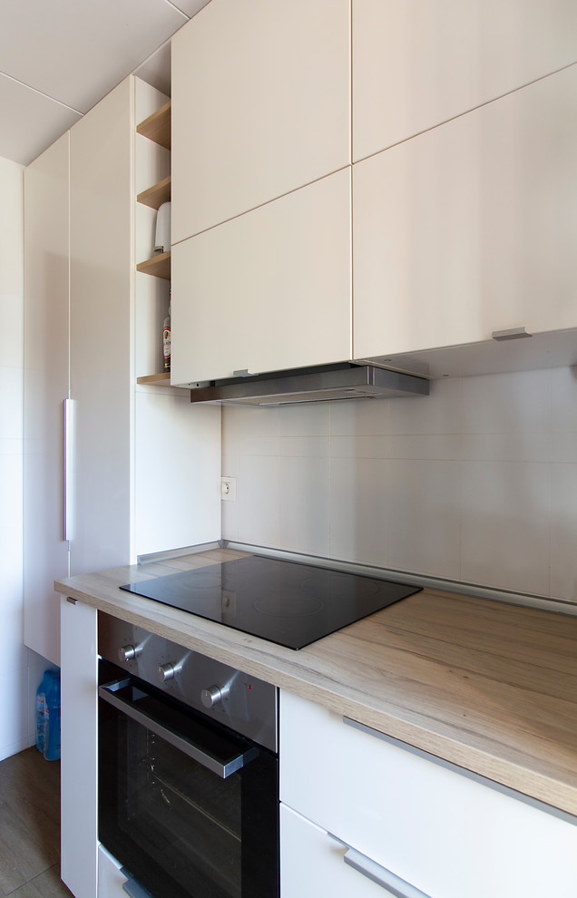 Enclosed kitchen - small scandinavian galley linoleum floor and brown floor enclosed kitchen idea in Barcelona with a double-bowl sink, flat-panel cabinets, white cabinets, laminate countertops, white backsplash, ceramic backsplash and stainless steel appliances