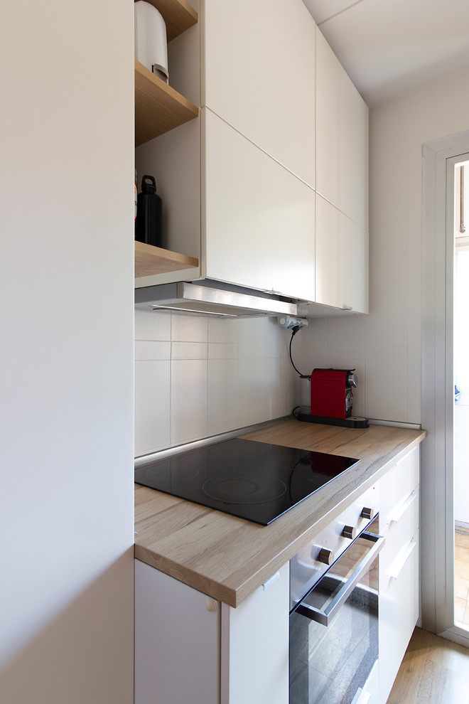 バルセロナにある低価格の小さな北欧スタイルのおしゃれなキッチン (ダブルシンク、フラットパネル扉のキャビネット、白いキャビネット、ラミネートカウンター、白いキッチンパネル、セラミックタイルのキッチンパネル、シルバーの調理設備、リノリウムの床、茶色い床) の写真