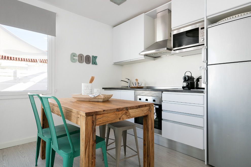 バルセロナにあるお手頃価格の小さな地中海スタイルのおしゃれなキッチン (シングルシンク、フラットパネル扉のキャビネット、白いキャビネット、白いキッチンパネル、淡色無垢フローリング、アイランドなし) の写真