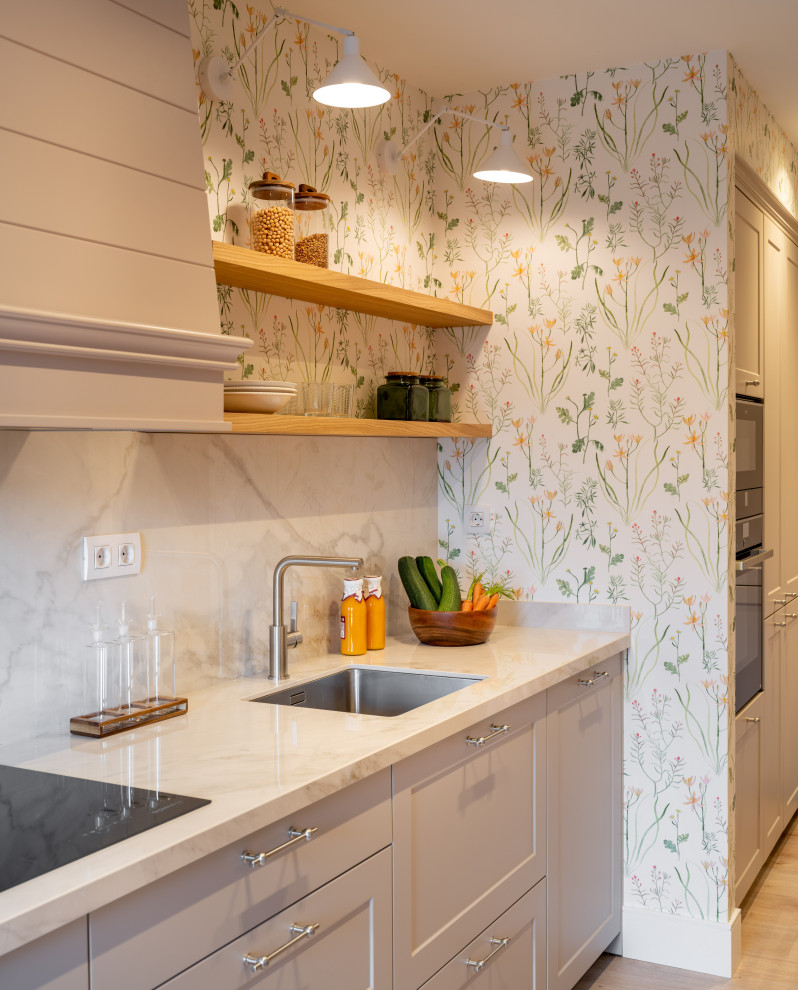 Klassisk inredning av ett mellanstort vit linjärt vitt kök och matrum, med en undermonterad diskho, luckor med upphöjd panel, grå skåp, bänkskiva i kvarts, vitt stänkskydd, rostfria vitvaror, laminatgolv och brunt golv