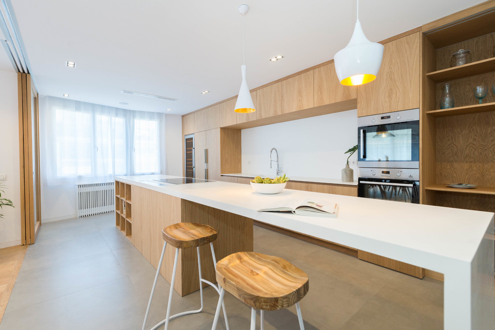 Zweizeilige Moderne Küche mit integriertem Waschbecken, flächenbündigen Schrankfronten, hellen Holzschränken, Küchenrückwand in Weiß, Küchengeräten aus Edelstahl, Kücheninsel, grauem Boden und weißer Arbeitsplatte in Madrid