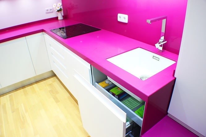 На фото: кухня в стиле модернизм с врезной мойкой, столешницей из кварцевого агломерата, розовым фартуком, фартуком из каменной плиты, белой техникой и светлым паркетным полом