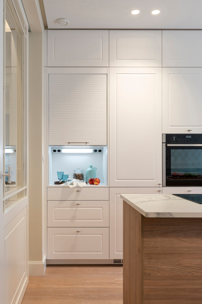 Idéer för mellanstora vintage vitt kök, med en undermonterad diskho, luckor med upphöjd panel, vita skåp, bänkskiva i kvarts, vitt stänkskydd, integrerade vitvaror, laminatgolv, en halv köksö och brunt golv