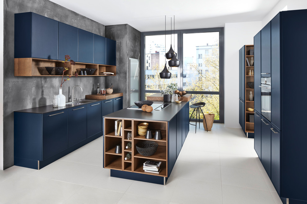 Cette photo montre une cuisine tendance avec un placard à porte plane, des portes de placard bleues, îlot, un évier 2 bacs, une crédence grise et un sol blanc.