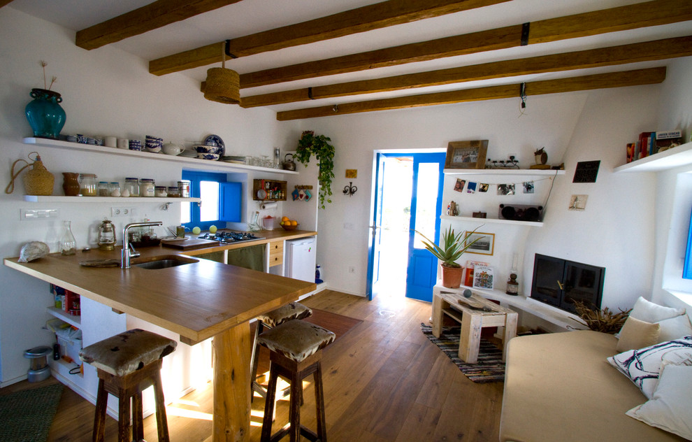 Exemple d'une cuisine américaine méditerranéenne en L de taille moyenne avec un évier 1 bac, un placard sans porte, un plan de travail en bois, un sol en bois brun et une péninsule.