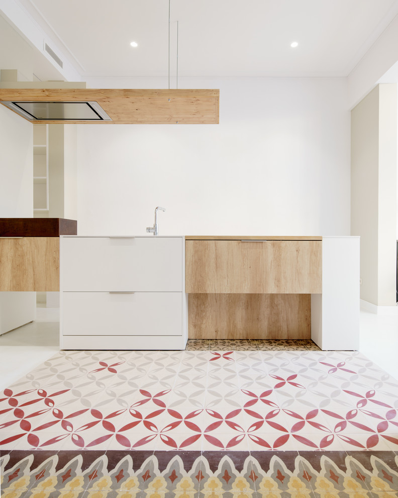 Diseño de cocina lineal mediterránea de tamaño medio abierta con armarios con paneles lisos, puertas de armario de madera clara, encimera de cuarcita y una isla