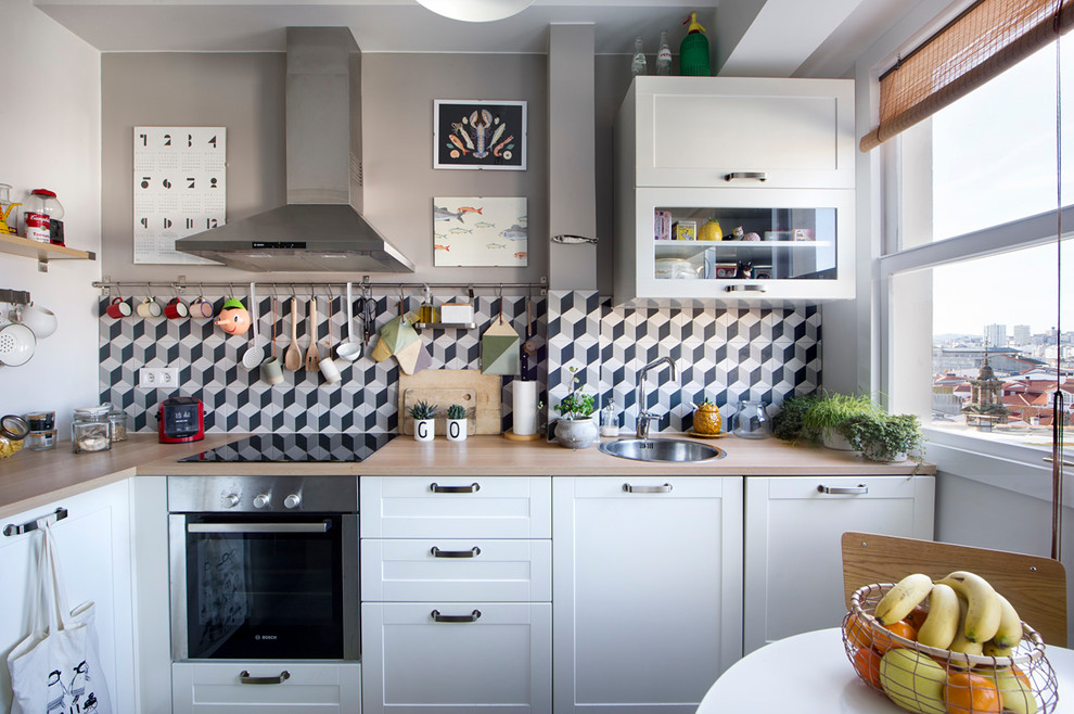 Small eclectic l-shaped eat-in kitchen photo in Madrid with a single-bowl sink, recessed-panel cabinets, white cabinets, wood countertops, multicolored backsplash, ceramic backsplash, stainless steel appliances and no island