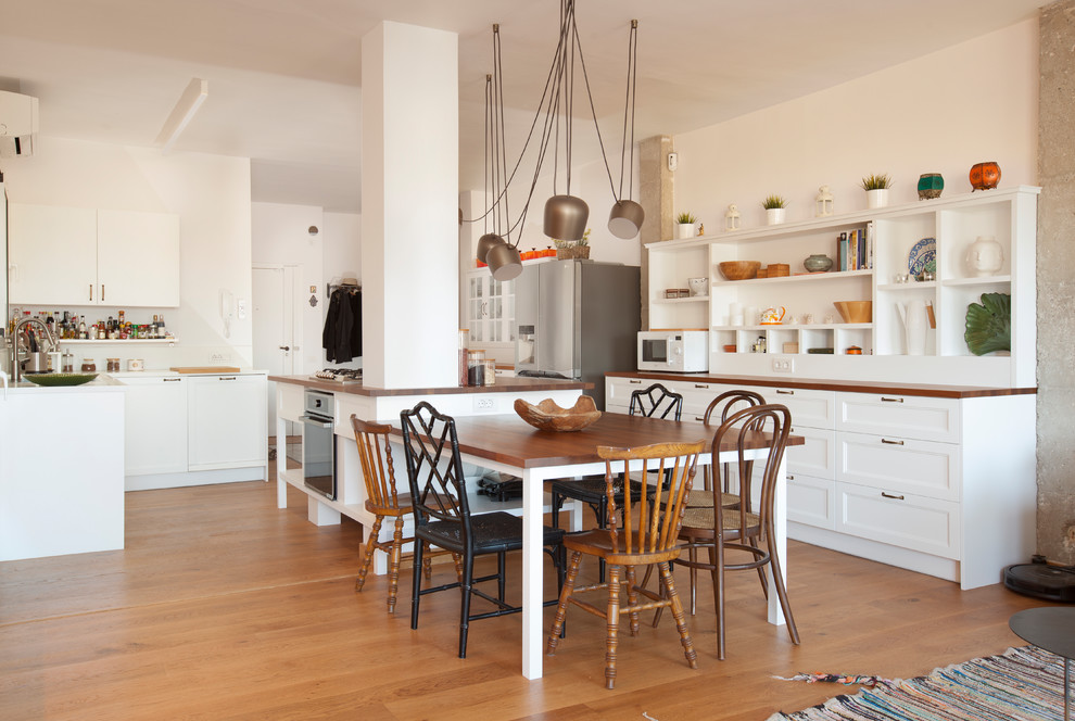 バルセロナにあるトランジショナルスタイルのおしゃれなキッチン (シェーカースタイル扉のキャビネット、白いキャビネット、木材カウンター、シルバーの調理設備、淡色無垢フローリング、ベージュの床、茶色いキッチンカウンター) の写真