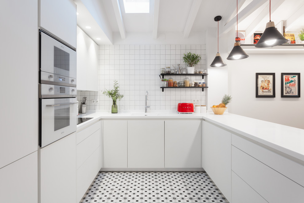 Example of a trendy u-shaped multicolored floor, exposed beam and vaulted ceiling kitchen design in Other with an integrated sink, flat-panel cabinets, white cabinets, white backsplash, white appliances, a peninsula and white countertops