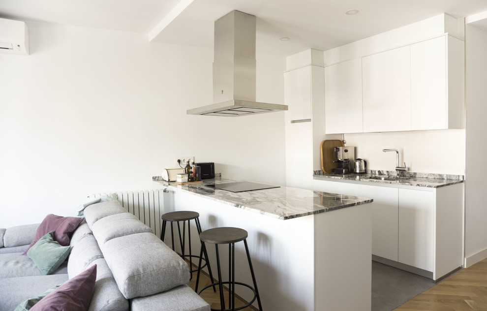 Example of a mid-sized danish single-wall medium tone wood floor open concept kitchen design in Madrid with an undermount sink, flat-panel cabinets, white cabinets, marble countertops, stainless steel appliances and an island
