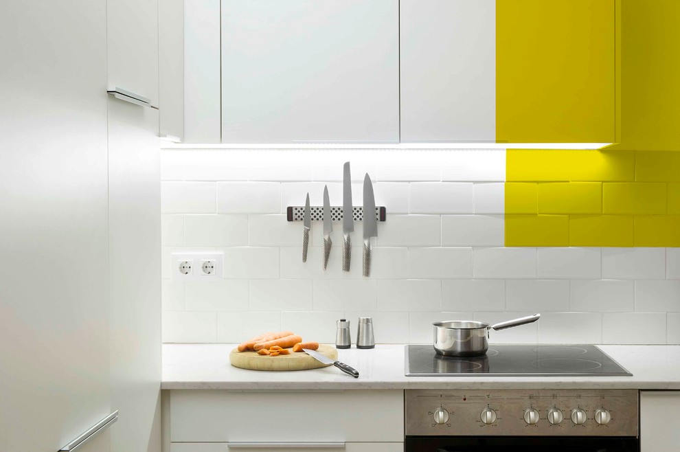 Kleine Moderne Wohnküche ohne Insel in L-Form mit Waschbecken, flächenbündigen Schrankfronten, weißen Schränken, Küchengeräten aus Edelstahl und braunem Holzboden in Barcelona