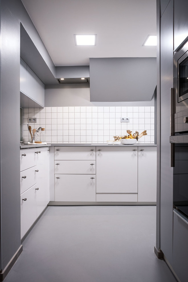 Diseño de cocina actual grande sin isla con armarios con paneles lisos, puertas de armario blancas, salpicadero blanco y electrodomésticos de acero inoxidable