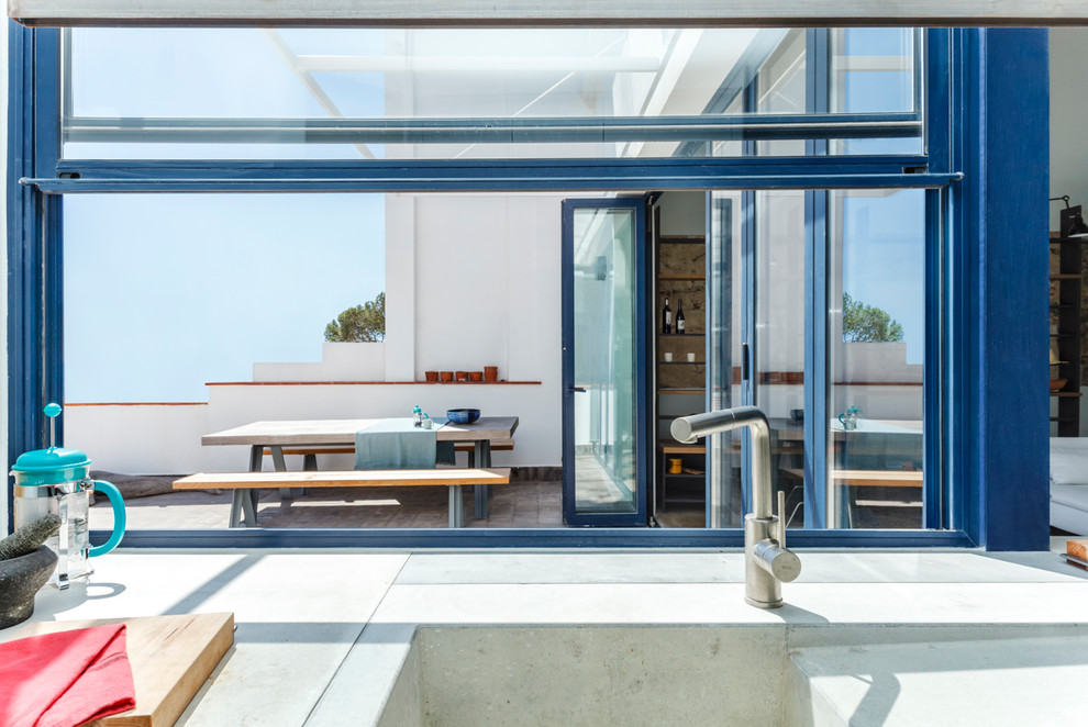 Diseño de cocina lineal mediterránea de tamaño medio abierta con puertas de armario grises, salpicadero azul y península