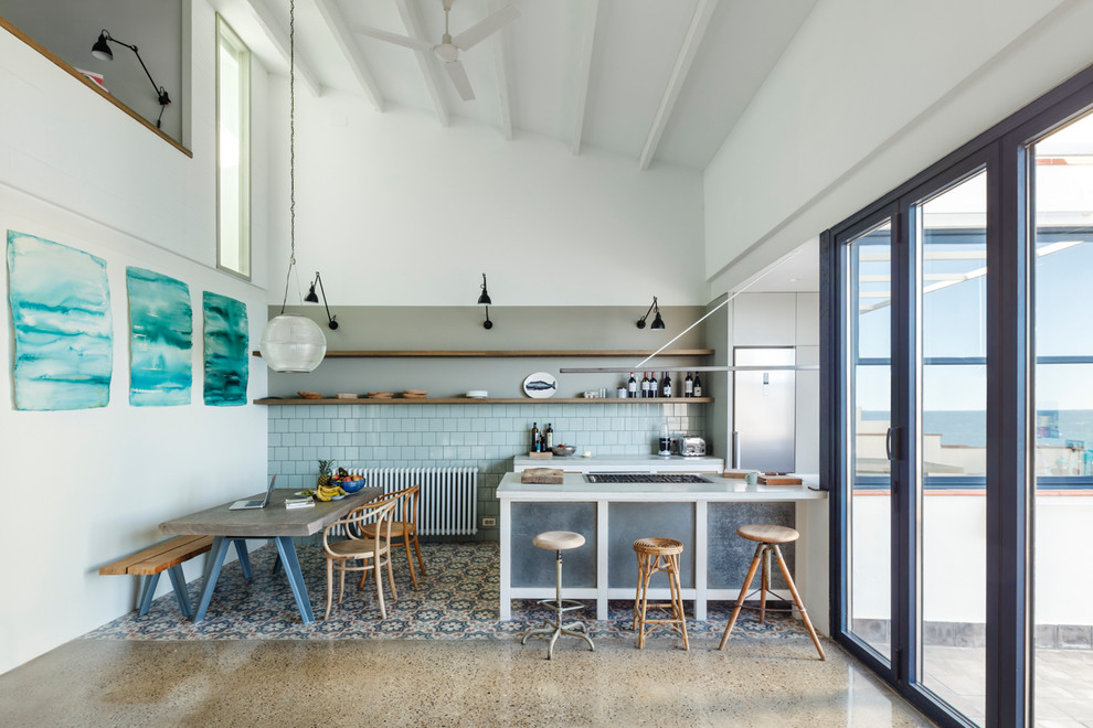 Foto de cocina lineal mediterránea de tamaño medio abierta con puertas de armario grises, salpicadero azul y península