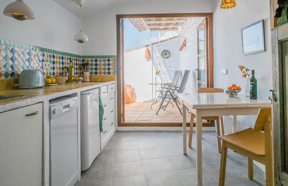 Medium sized mediterranean single-wall enclosed kitchen in Malaga with flat-panel cabinets, white cabinets, tile countertops, multi-coloured splashback, ceramic splashback, ceramic flooring and no island.