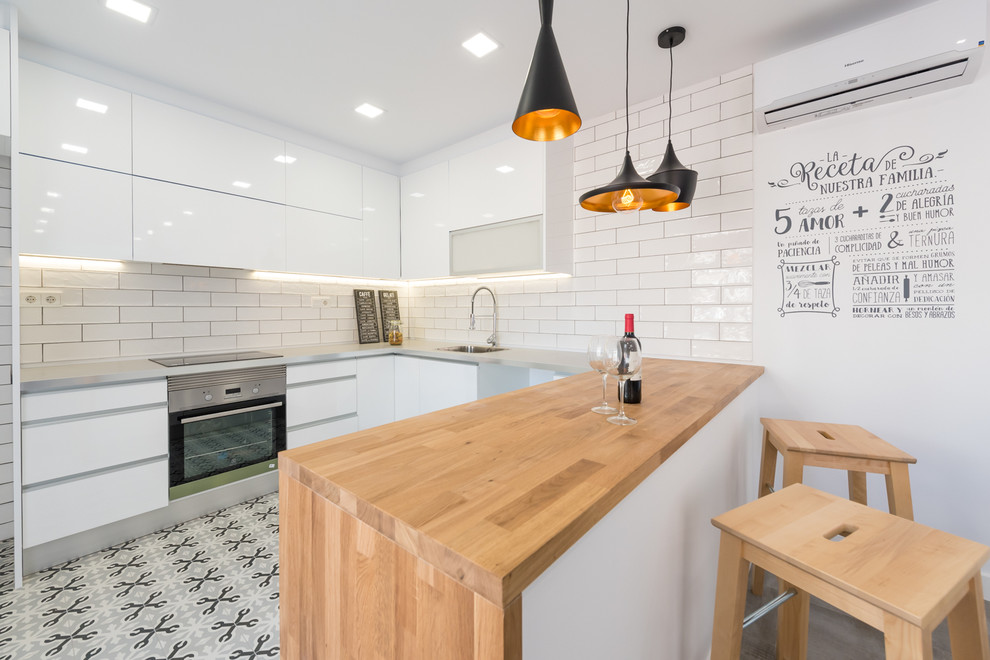 Example of a mid-sized trendy u-shaped open concept kitchen design in Palma de Mallorca with an integrated sink, flat-panel cabinets, white cabinets, wood countertops, white backsplash, subway tile backsplash, stainless steel appliances and a peninsula