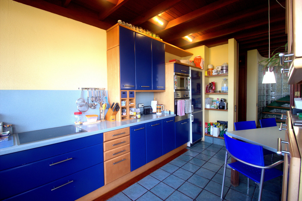他の地域にある低価格の広いコンテンポラリースタイルのおしゃれなキッチン (シングルシンク、フラットパネル扉のキャビネット、青いキャビネット、クオーツストーンカウンター、青いキッチンパネル、パネルと同色の調理設備、セラミックタイルの床、青い床、青いキッチンカウンター) の写真