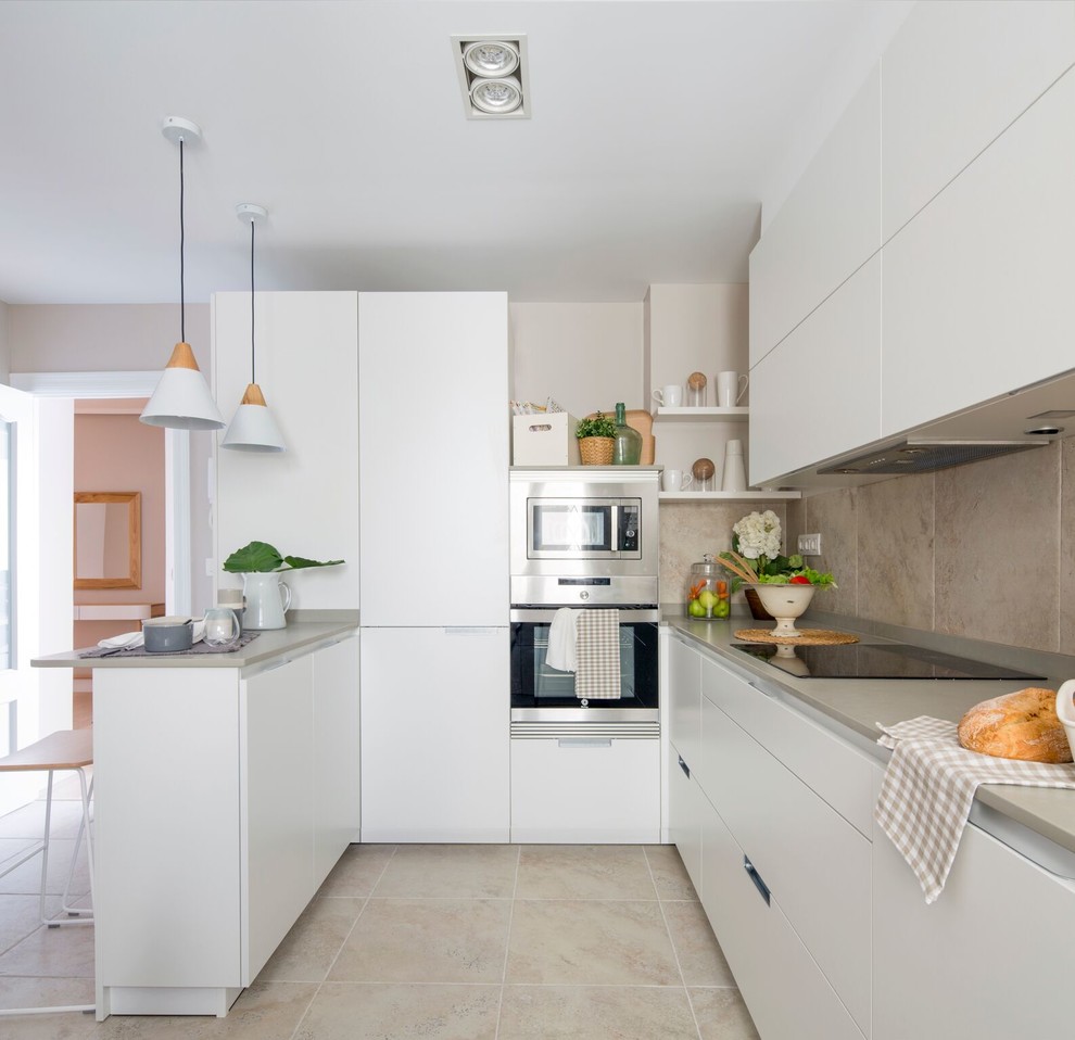 Foto di una cucina minimalista di medie dimensioni con ante lisce, ante bianche, elettrodomestici in acciaio inossidabile, penisola, pavimento beige e top grigio
