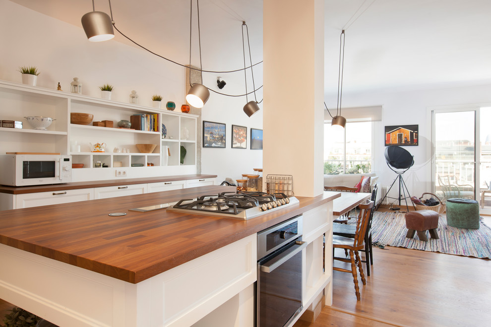 На фото: большая параллельная кухня-гостиная в стиле модернизм с фасадами с утопленной филенкой, белыми фасадами, деревянной столешницей, островом и коричневым полом