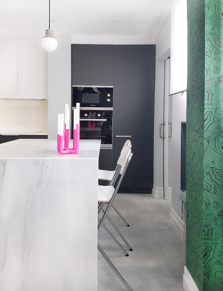 На фото: угловая кухня-гостиная среднего размера в современном стиле с врезной мойкой, плоскими фасадами, серыми фасадами, мраморной столешницей, белым фартуком, бетонным полом, островом и серым полом с