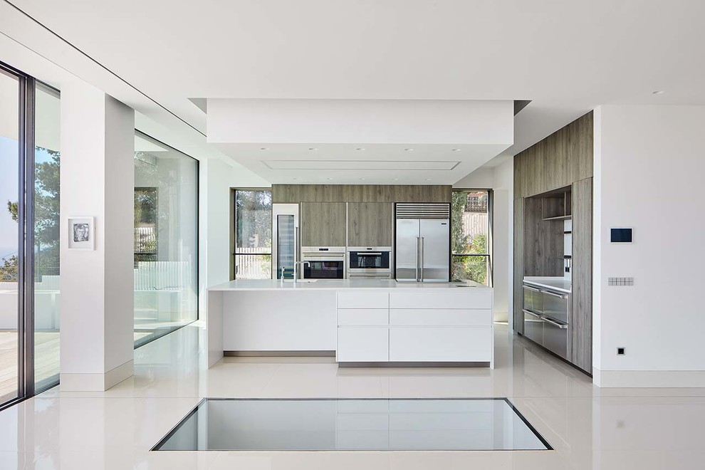 Cette image montre une grande cuisine ouverte linéaire minimaliste avec un placard à porte plane, des portes de placard blanches et îlot.