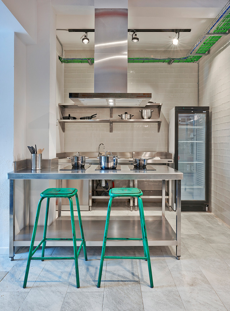 Diseño de cocinas en U urbano con puertas de armario en acero inoxidable, encimera de acero inoxidable y salpicadero blanco
