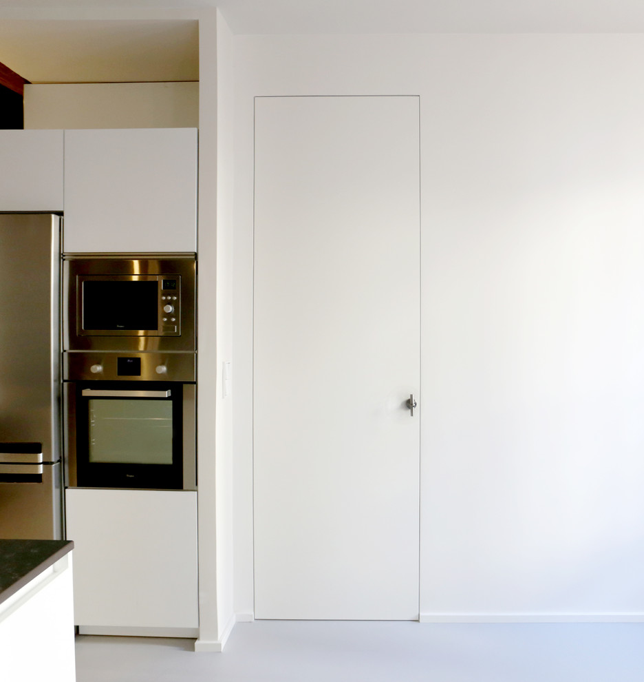 На фото: кухня-гостиная среднего размера в современном стиле с плоскими фасадами, полом из линолеума, островом, серым полом, черной столешницей и балками на потолке с