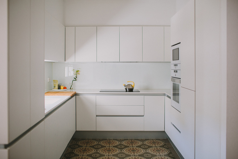 Inspiration för ett litet funkis u-kök, med släta luckor, vita skåp, vitt stänkskydd, vita vitvaror, klinkergolv i keramik och flerfärgat golv