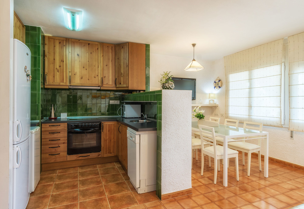 Offene, Kleine Maritime Küche ohne Insel in L-Form mit profilierten Schrankfronten, hellbraunen Holzschränken und Küchenrückwand in Grün in Sonstige