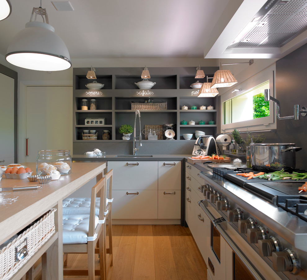Imagen de cocina urbana, de tamaño medio, sin isla, con fregadero bajoencimera, armarios abiertos, puertas de armario grises, encimera de acrílico, salpicadero verde, electrodomésticos de acero inoxidable y suelo de madera en tonos medios