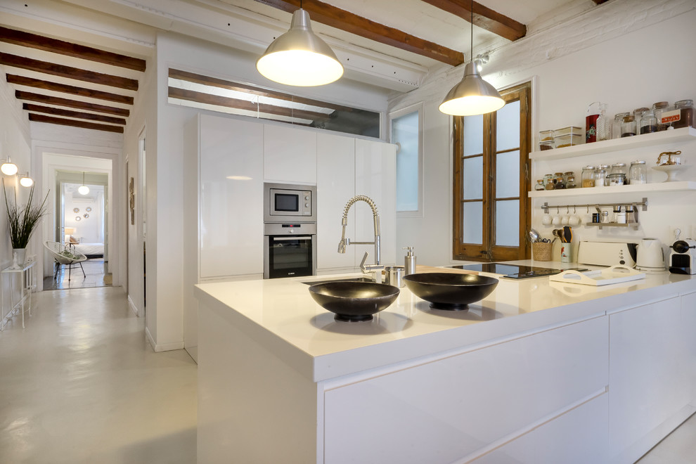 Foto på ett stort medelhavsstil vit linjärt kök med öppen planlösning, med släta luckor, vita skåp, rostfria vitvaror, en halv köksö, en undermonterad diskho, betonggolv och grått golv