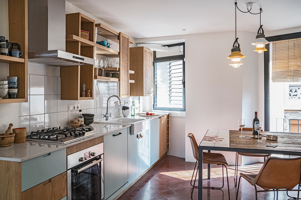 Foto på ett litet medelhavsstil linjärt kök och matrum, med en enkel diskho, öppna hyllor, blå skåp, bänkskiva i kvarts, vitt stänkskydd, stänkskydd i keramik, rostfria vitvaror och betonggolv