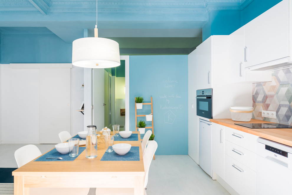 Example of a mid-sized beach style single-wall white floor eat-in kitchen design in Valencia with flat-panel cabinets, white cabinets, wood countertops, multicolored backsplash, no island and brown countertops