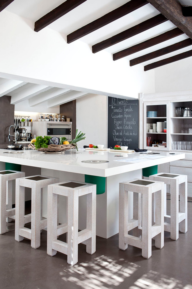 Design ideas for a large mediterranean l-shaped enclosed kitchen in Madrid with open cabinets, white cabinets, concrete flooring, an island, composite countertops and stainless steel appliances.