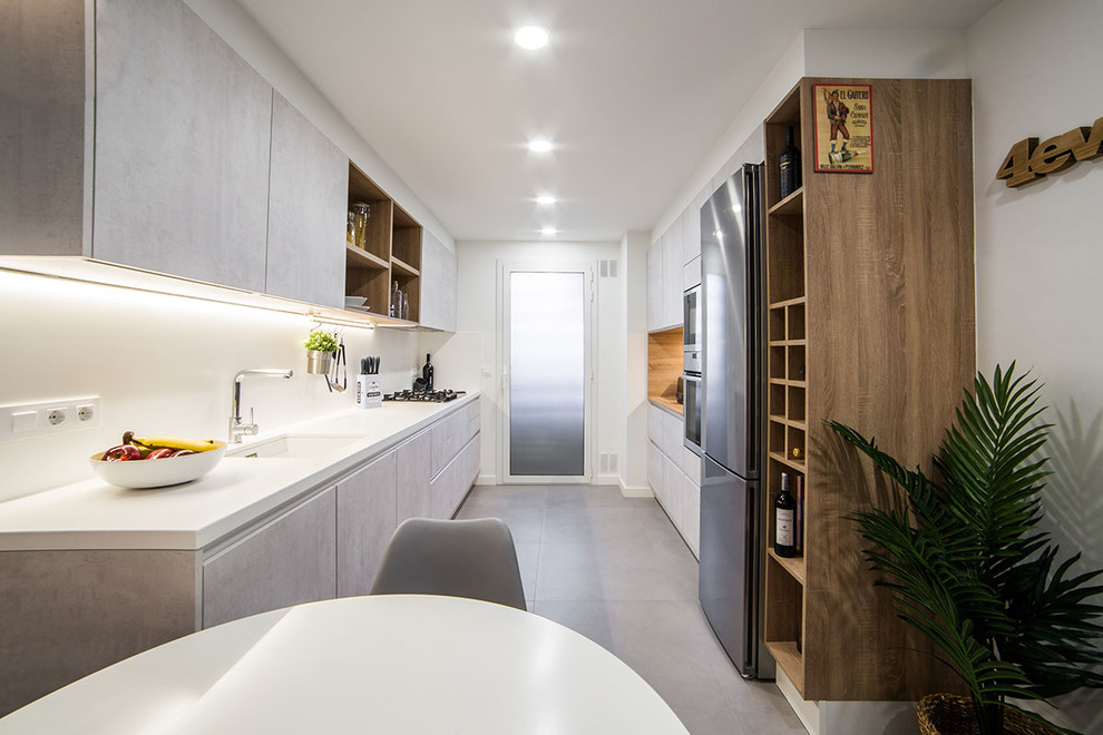 Example of a trendy galley gray floor eat-in kitchen design in Barcelona with flat-panel cabinets, white backsplash, no island, white countertops, an undermount sink, gray cabinets and stainless steel appliances