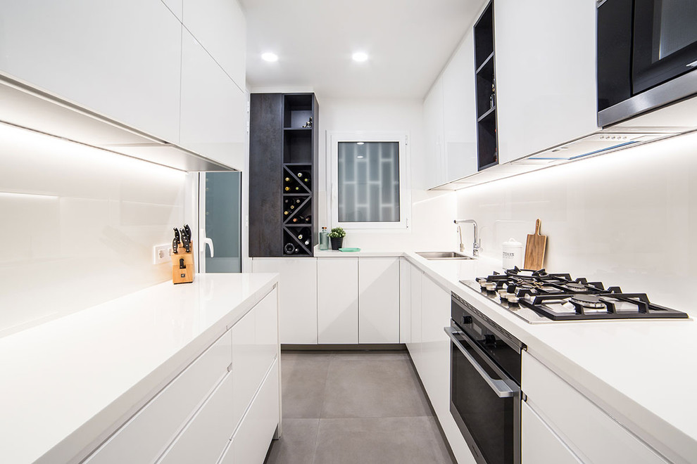 Inspiration for a contemporary l-shaped gray floor kitchen remodel in Barcelona with a double-bowl sink, flat-panel cabinets, white cabinets, white backsplash, black appliances, no island and white countertops