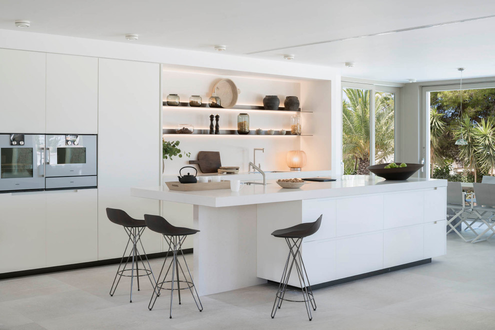 Ejemplo de cocina contemporánea con fregadero bajoencimera, armarios con paneles lisos, puertas de armario blancas, una isla, suelo gris y encimeras blancas
