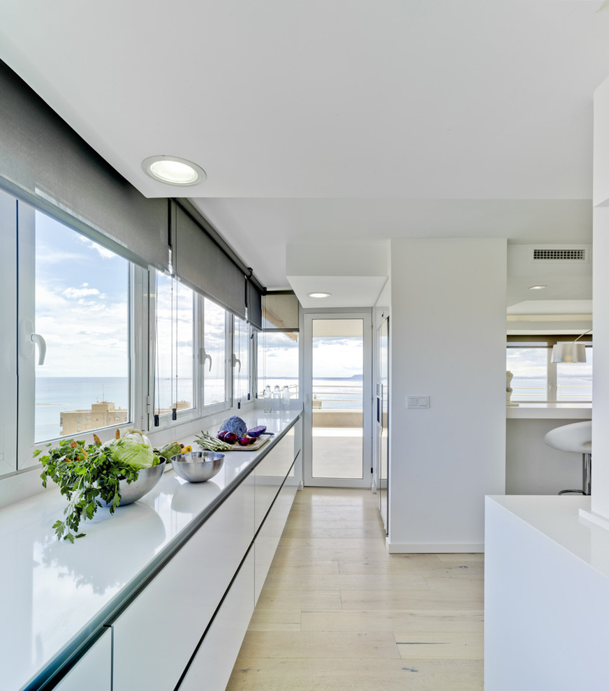 Ejemplo de cocina lineal marinera de tamaño medio abierta sin isla con armarios con paneles lisos y puertas de armario blancas