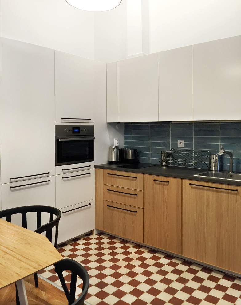 マドリードにある低価格の小さなコンテンポラリースタイルのおしゃれなキッチン (シングルシンク、フラットパネル扉のキャビネット、中間色木目調キャビネット、青いキッチンパネル、セラミックタイルのキッチンパネル、パネルと同色の調理設備、セメントタイルの床、赤い床) の写真