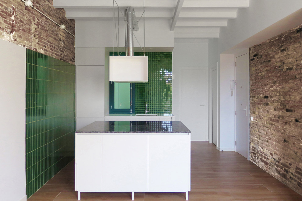 Exemple d'une cuisine ouverte linéaire industrielle de taille moyenne avec un évier 1 bac, un placard à porte plane, des portes de placard blanches, une crédence verte, un sol en bois brun et îlot.