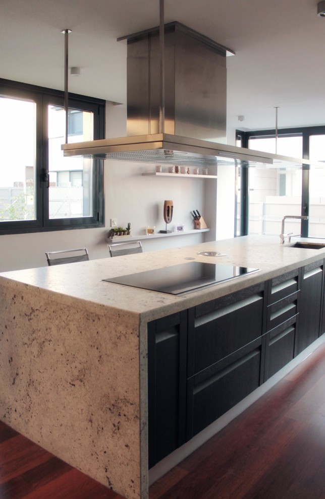 Foto på ett stort funkis linjärt kök och matrum, med en undermonterad diskho, släta luckor, svarta skåp, granitbänkskiva, rostfria vitvaror, mellanmörkt trägolv och en köksö