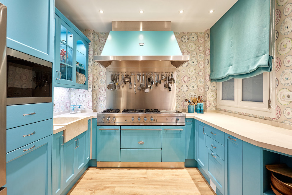 Mid-sized transitional u-shaped light wood floor and beige floor enclosed kitchen photo in Madrid with blue cabinets, multicolored backsplash and stainless steel appliances