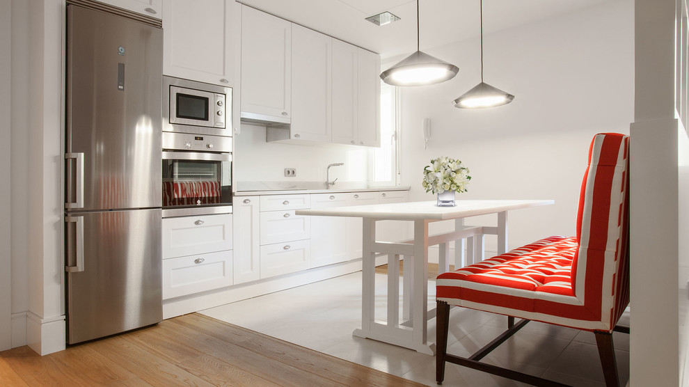 Einzeilige, Mittelgroße Moderne Wohnküche ohne Insel mit profilierten Schrankfronten, weißen Schränken, Küchenrückwand in Weiß und Küchengeräten aus Edelstahl in Madrid