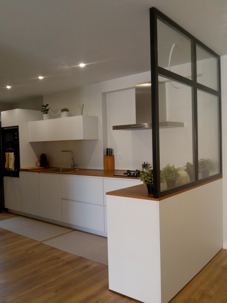 Photo of a medium sized scandi l-shaped open plan kitchen in Madrid with an integrated sink, flat-panel cabinets, white cabinets, wood worktops, ceramic splashback, stainless steel appliances, medium hardwood flooring and multiple islands.